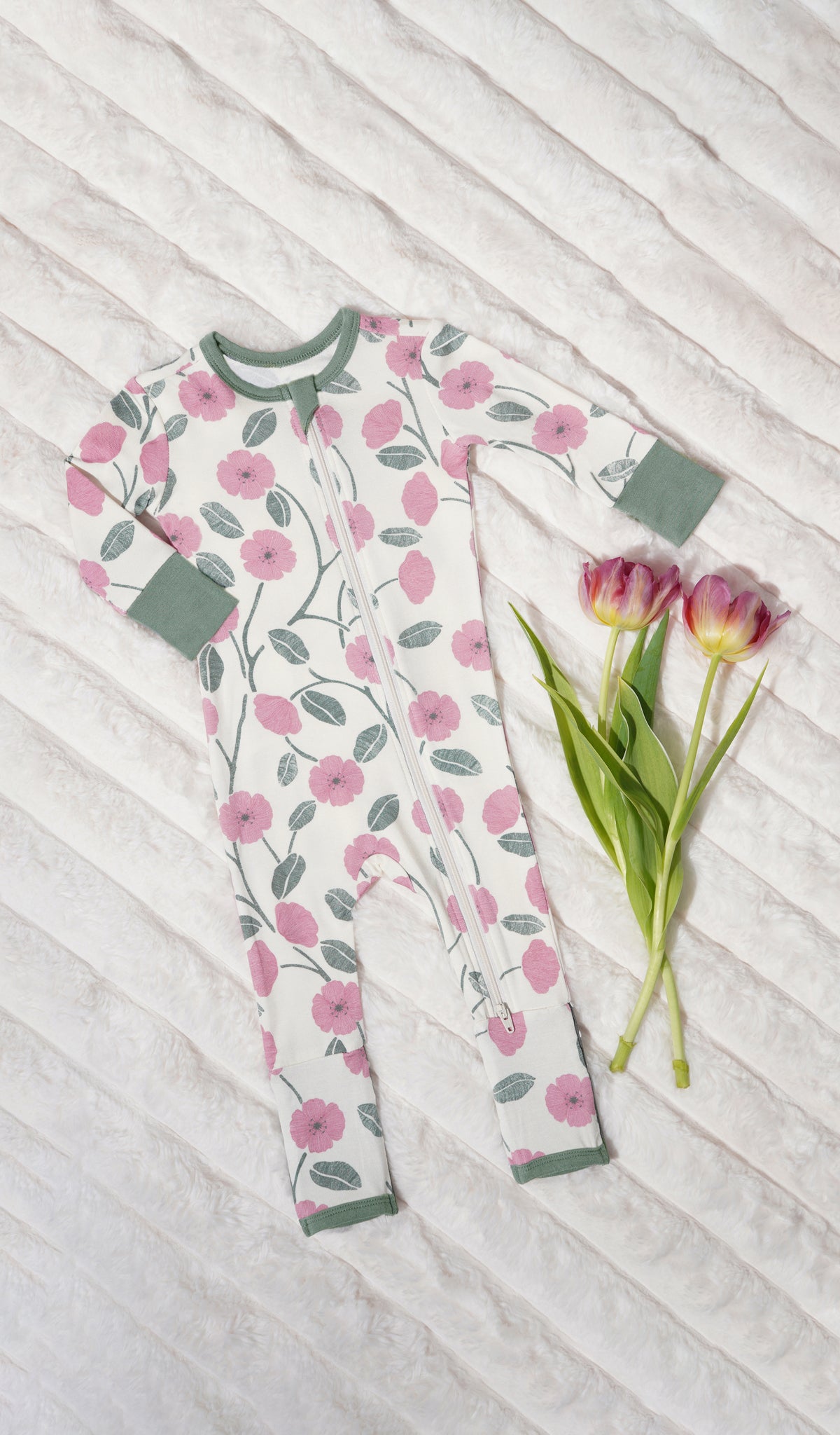 Honey Bloom Convertible Romper with long sleeves and zip front on soft beige blanket with flowers.