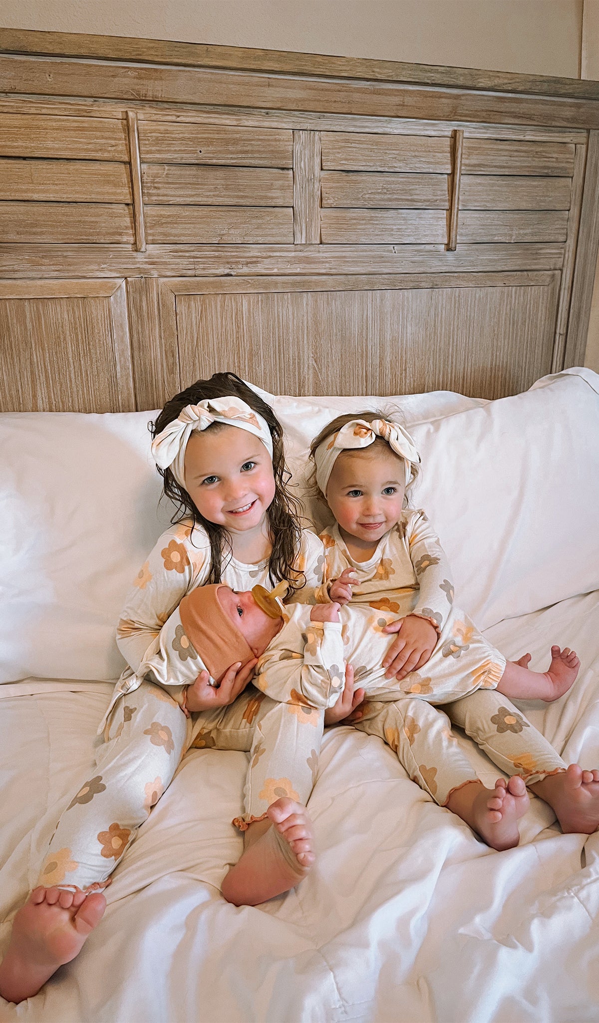 Daisies Charlie Kids 3-Piece Pant PJ worn by sisters matching while holding their newborn baby sister.