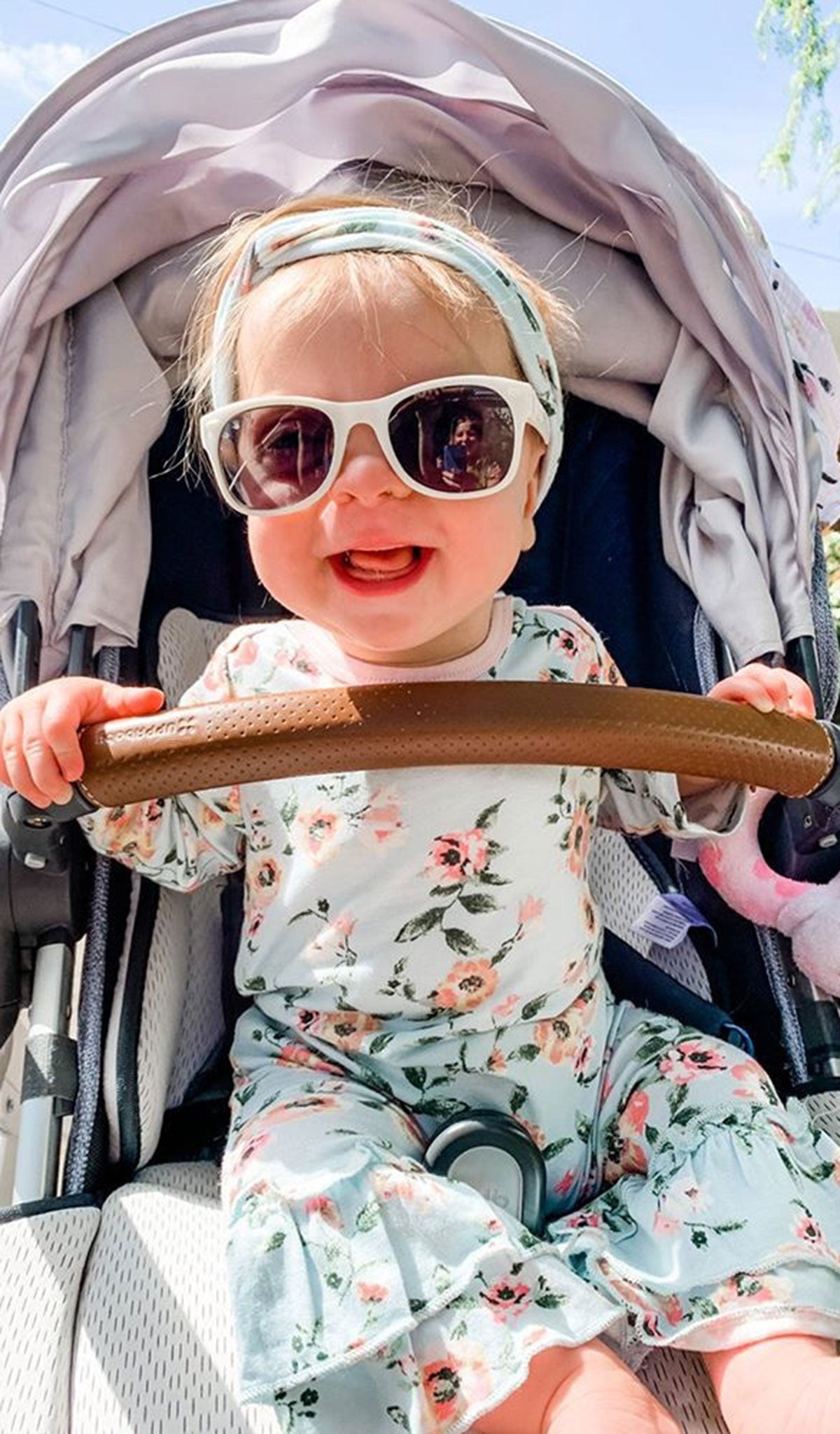 Cloud Blue Ruffle Romper 2-Piece on baby girl wearing sunglasses and matching headwrap while sitting in a baby stroller. 