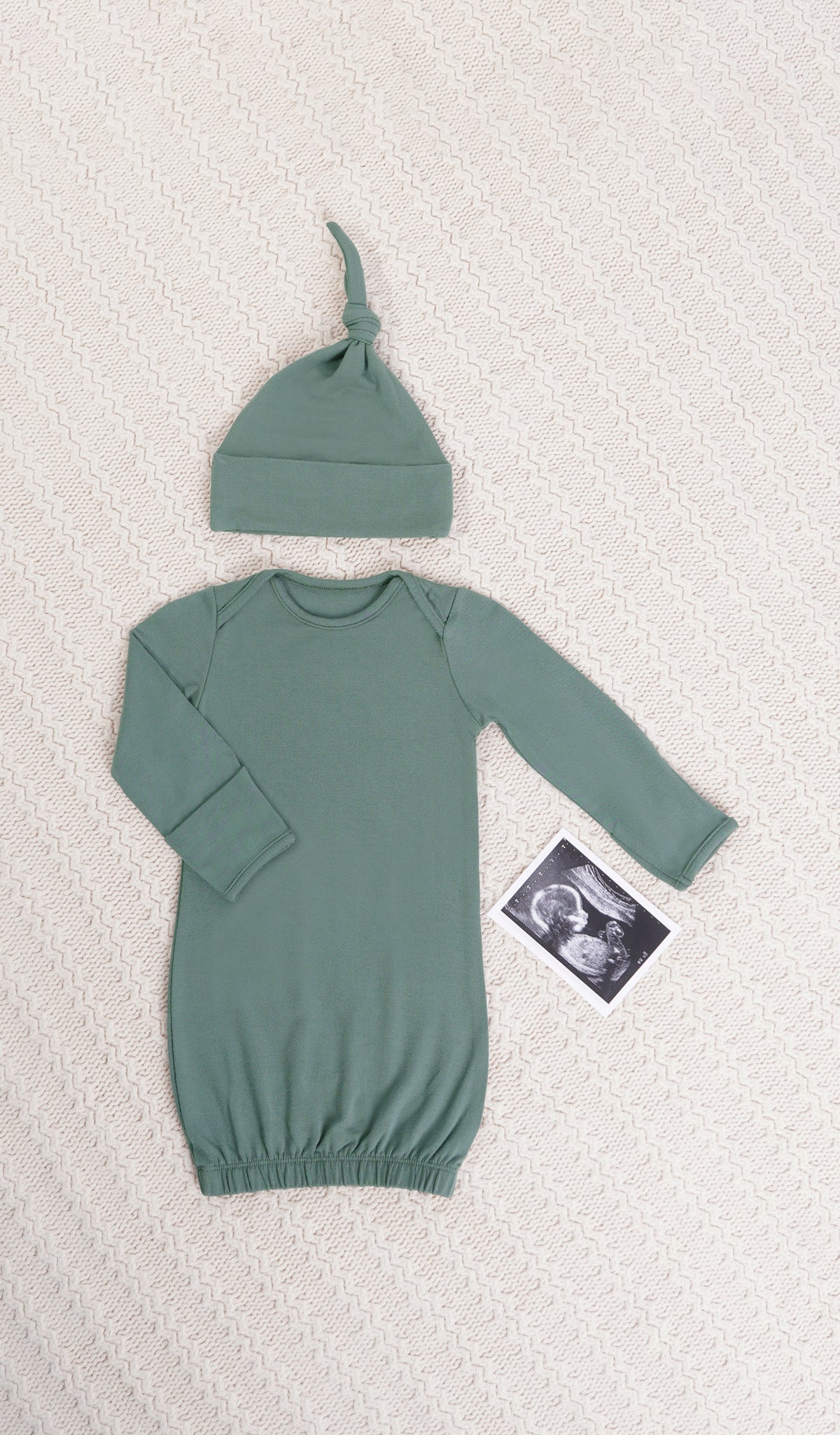 Fog Analise 5-Piece Set, gown and knotted hat for baby with ultrasound on a textured beige blanket.
