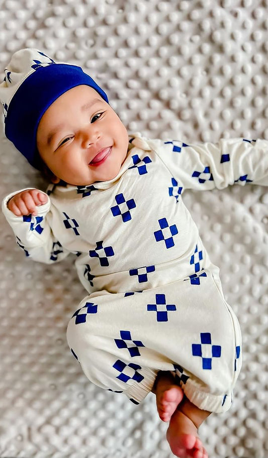 Geo Gown 2-Piece with long sleeve baby gown and matching knotted hat worn by smiling baby laying on bed.