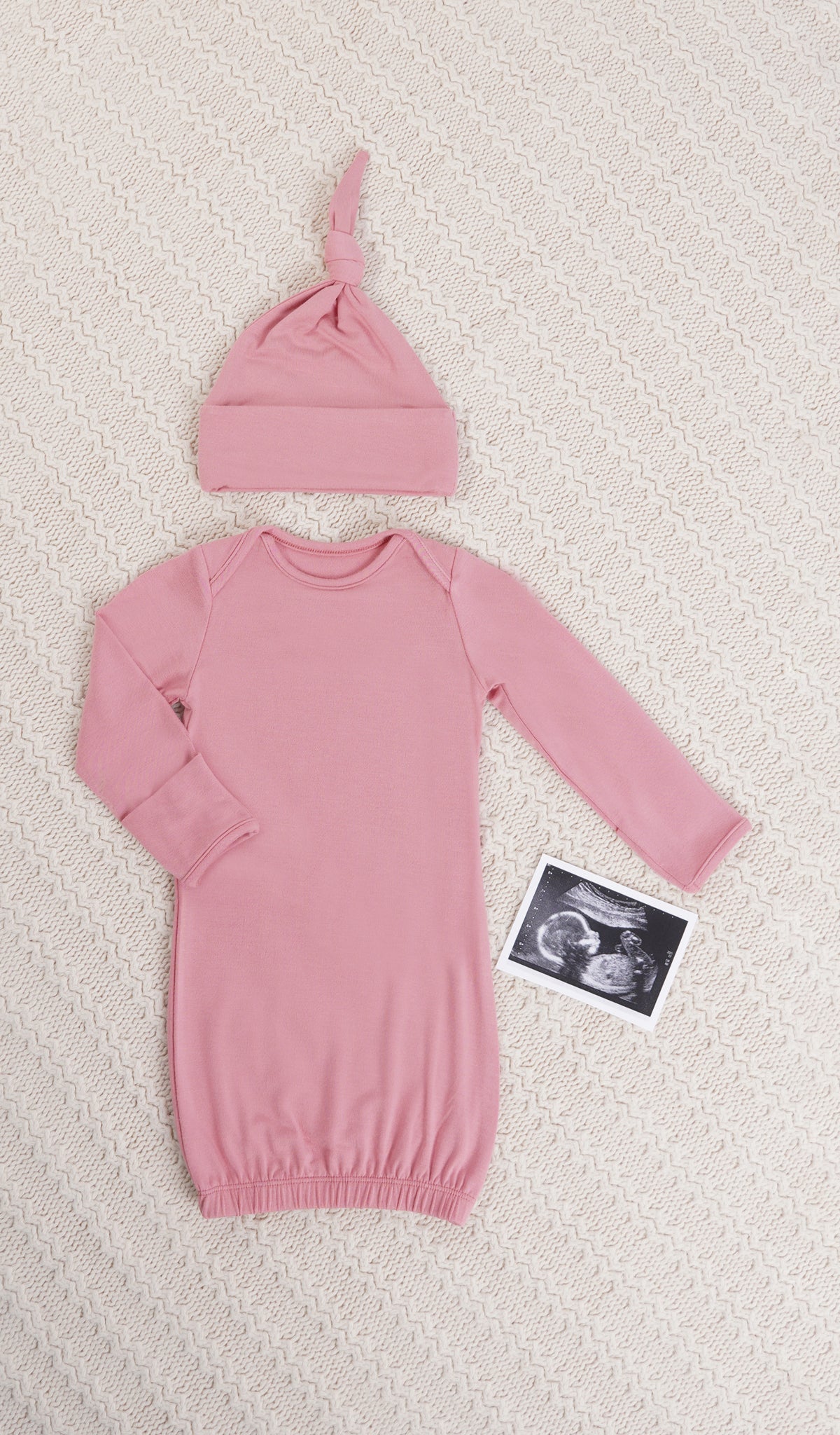 Rose Analise 5-Piece Set, gown and knotted hat for baby with ultrasound on a textured beige blanket.