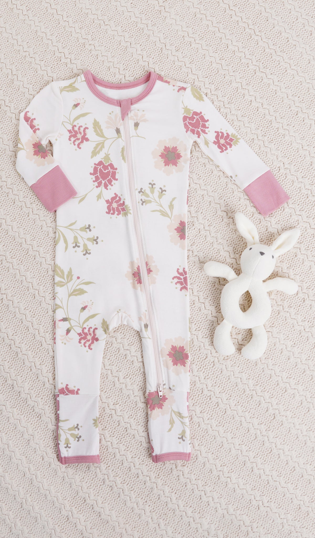 Cottage Floral Convertible Romper with long sleeves and zip front on knitted beige blanket with a bunny rattle.