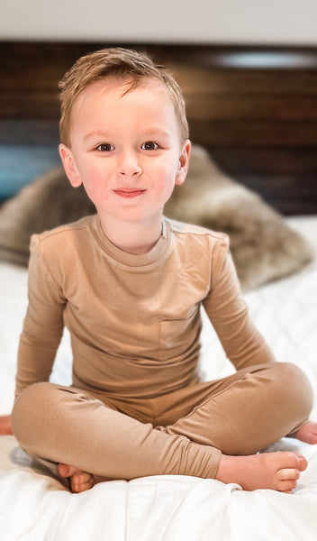 Latte Emerson Kids 2-Piece Pant PJ worn by a boy sitting on his bed.