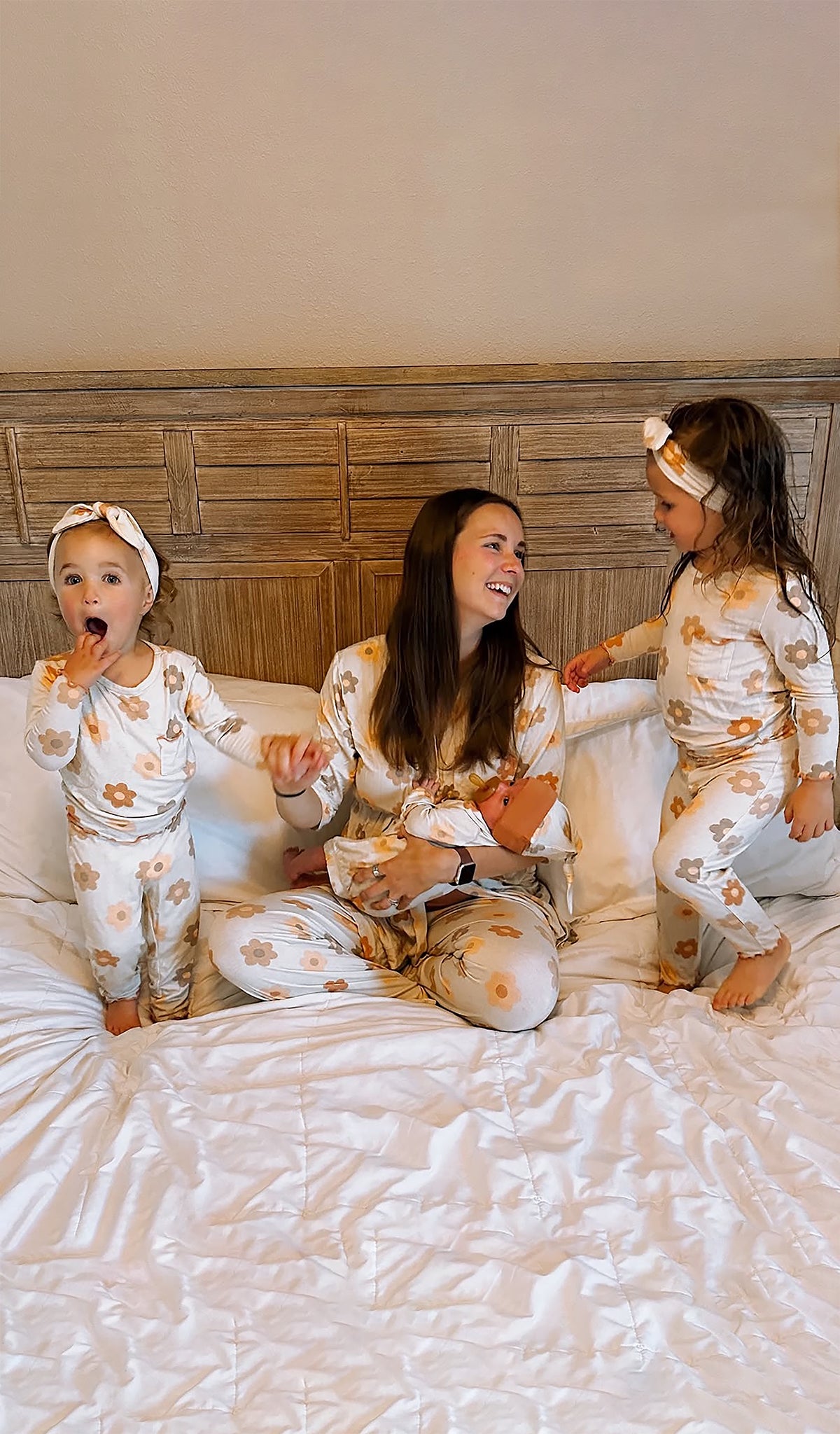 Woman and two children in matching pajamas sitting on a bed.
