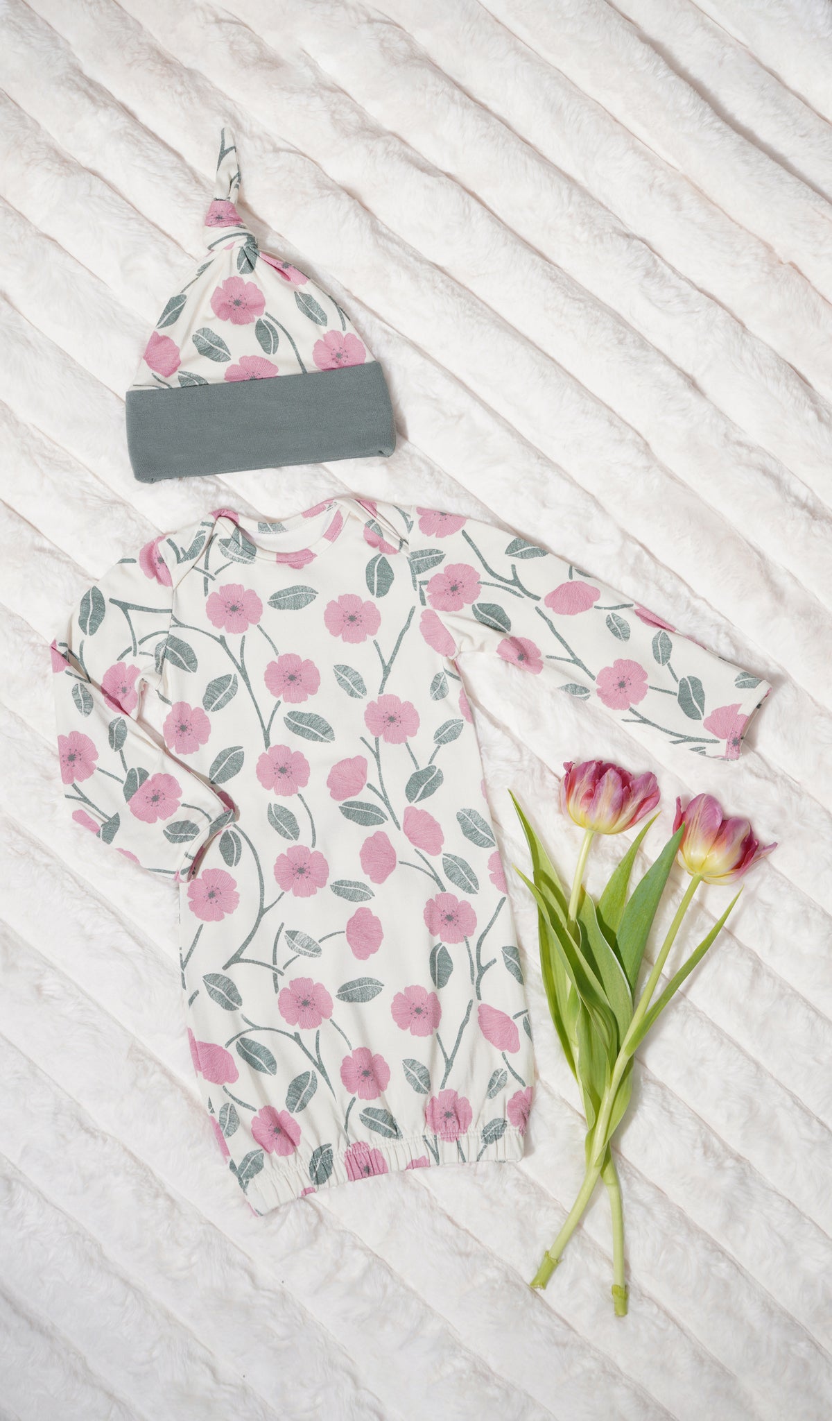 Honey Bloom Analise 5-Piece Set, gown and knotted hat for baby with flowers on a textured beige blanket.