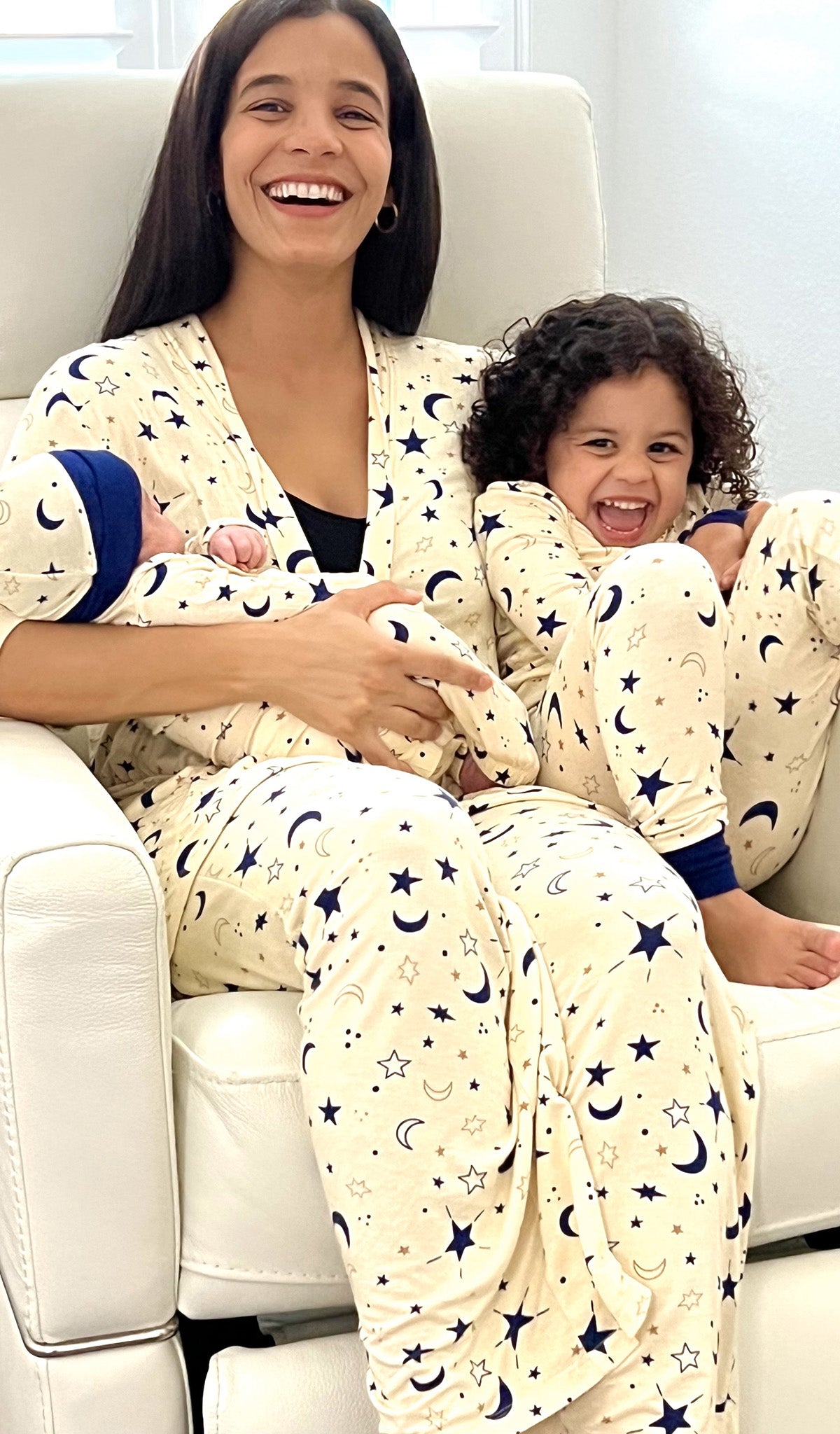 Twinkle Analise 5-Piece Set worn by mom in robe, tank and pant, while holding baby in matching gown and hat. Her son is sitting next to her in matching PJs too.. Pregnant woman wearing 3/4 sleeve robe, tank top and pant while holding a baby gown.