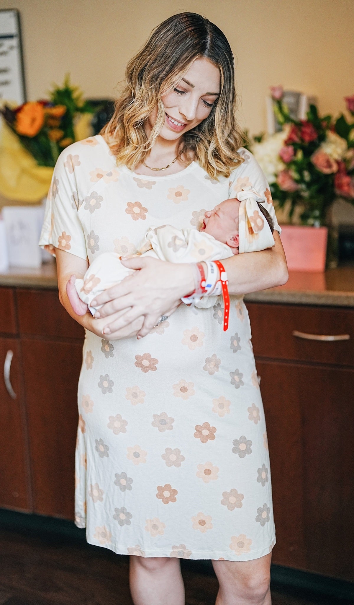 Daisies Rosa hospital gown worn by woman holding her newborn baby.