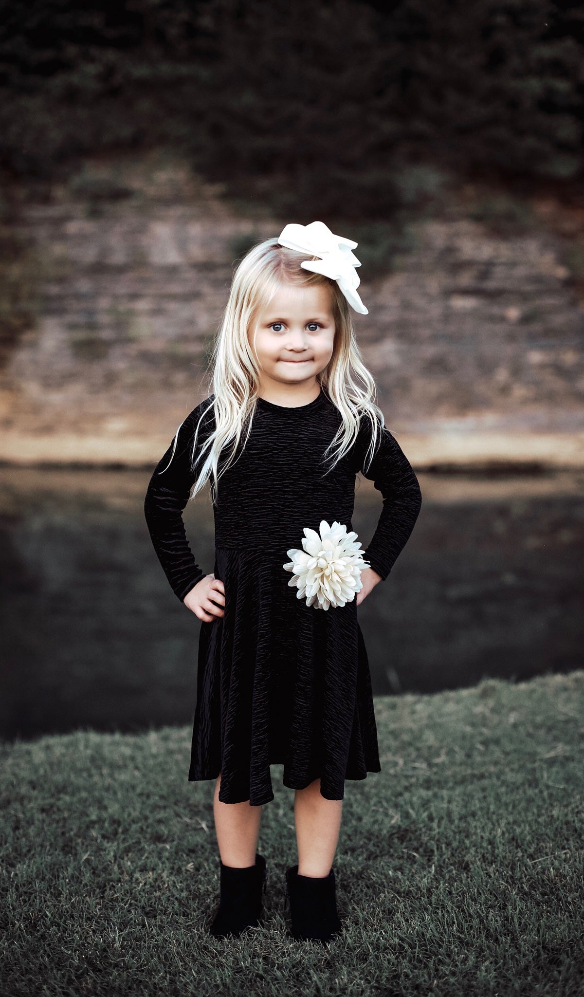 Black Kendyl Kids Twirly Dress worn by little girl with ivory bow in her hair.