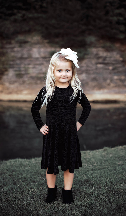 Kendyl black velvet dress worn by little girl with her hands on her hips.