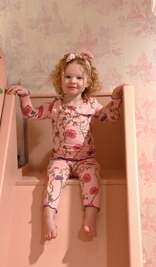 Dahlia Charlie Baby 3-Piece Pant PJ worn by baby girl sitting on pink furniture.