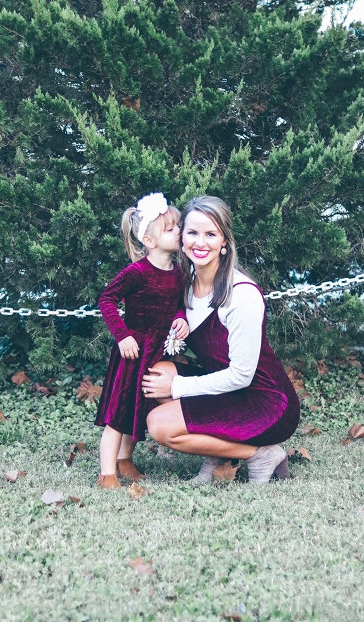 Merlot Aurora dress worn by woman with Cristiano long sleeve oatmeal top layered underneath who is kneeling next to little girl kissing her on the cheek wearing matching Kendyl Dress.