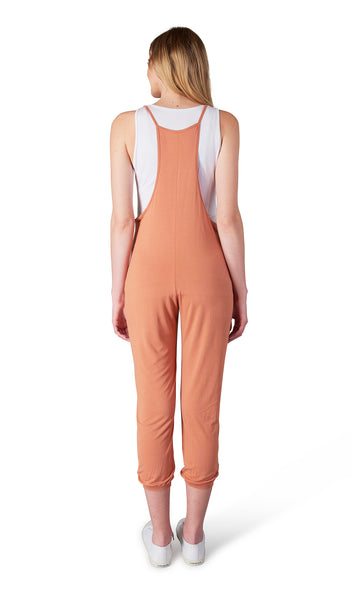 Sandstone Brandi Romper. Back shot of woman wearing Brandi romper over white Kara Tank and with tennis shoes.