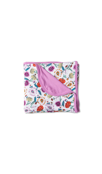 Zinnia Swaddle Blanket folded into a square with print showing on one side and reversible contrast solid showing on other side of fold down flap.