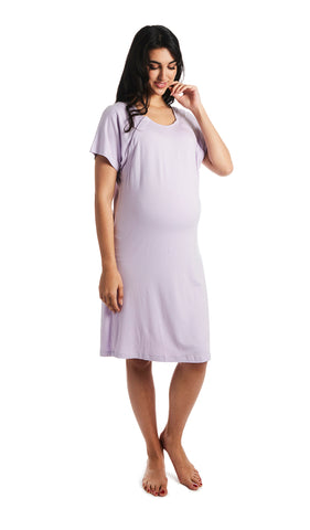 Lavender Rosa hospital gown. Pregnant woman wearing hospital gown with scoop-neckline featuring dual snap openings.  One hand is down to side with fingers of other hand touching chin. 