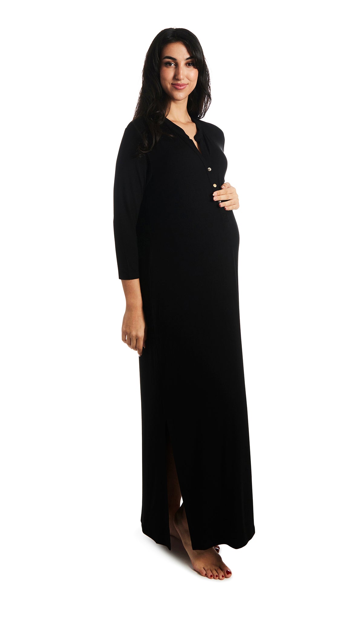 Black Juliana dress. Pregnant woman with one hand on belly wearing caftan featuring long sleeve button-up V-neckline with band collar and a maxi-length hem with airy side slits.