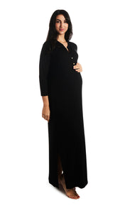 Black Juliana dress. Pregnant woman with one hand on belly wearing caftan featuring long sleeve button-up V-neckline with band collar and a maxi-length hem with airy side slits.