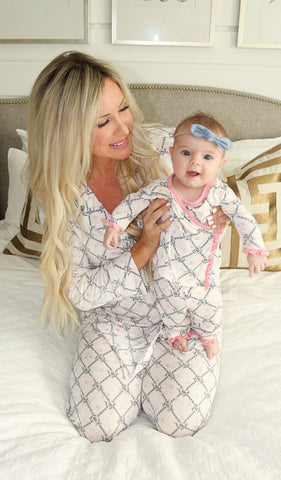 Duchess Baby's Ruffle Take-Me-Home set. Woman wearing Helen PJ in Duchess print is holding baby girl wearing matching Ruffle Take-Me-Home top and pant with blue hair bow.
