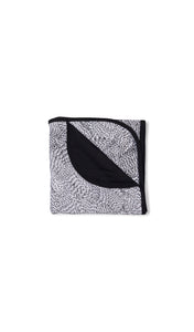 Twilight Swaddle Blanket folded into a square with print showing on one side and reversible contrast solid showing on other side of fold down flap.