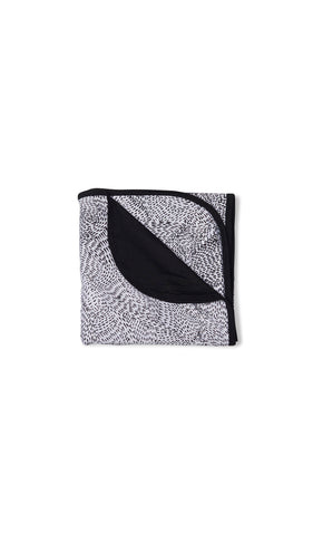Twilight Swaddle Blanket folded into a square with print showing on one side and reversible contrast solid showing on other side of fold down flap.