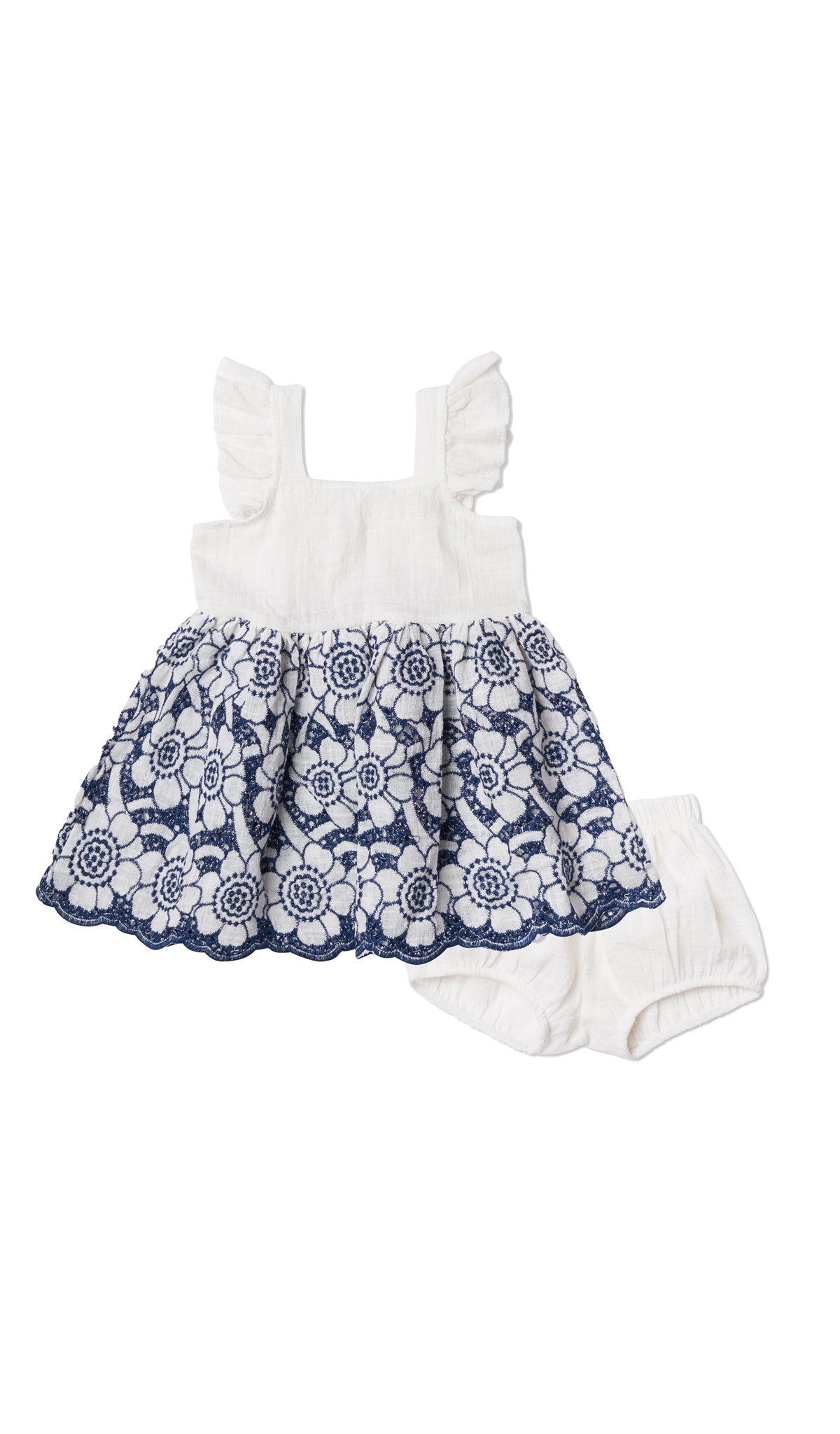 Ivory/Navy Eyelet Baby Dress. Flat shot of eyelet dress laying over the matching diaper cover.