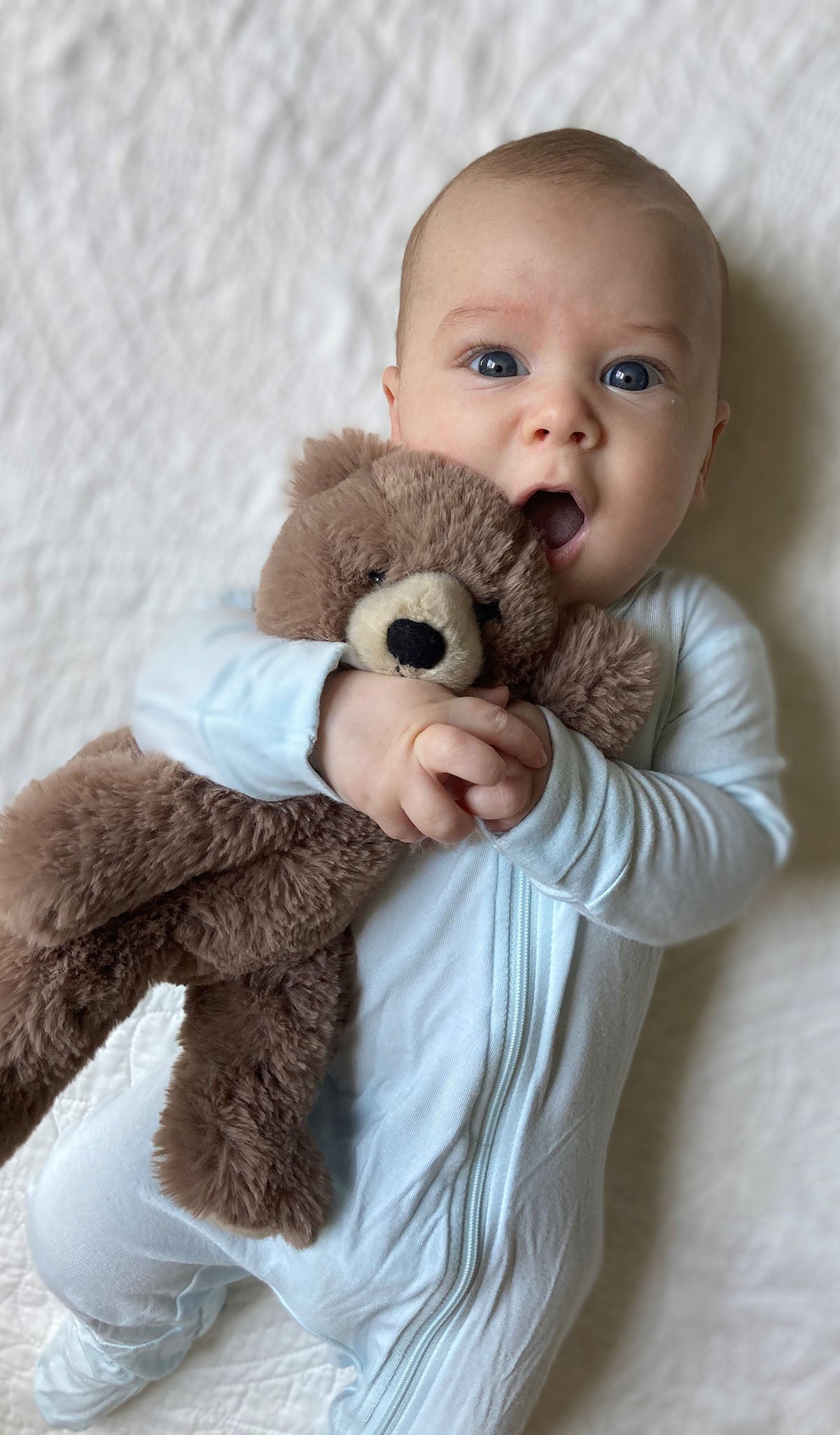 Whispering Blue Footie worn by baby holding teddy bear.