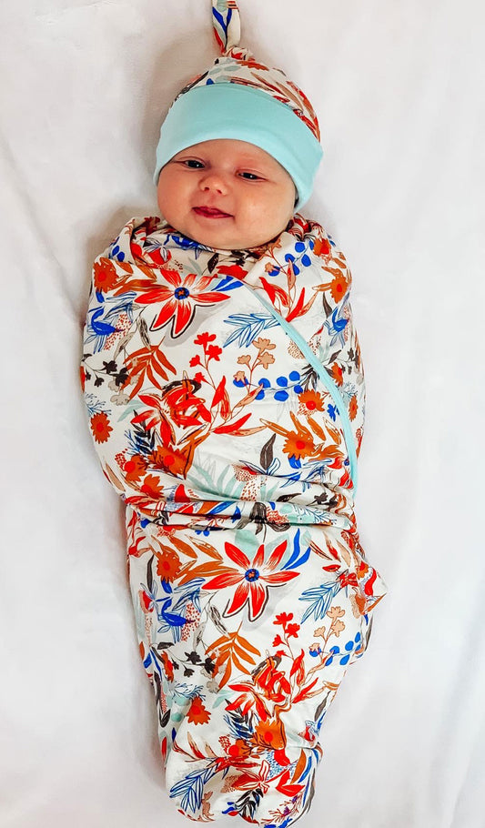 Posy Swaddle Blanket, baby swaddled in blanket wearing matching knotted hat.