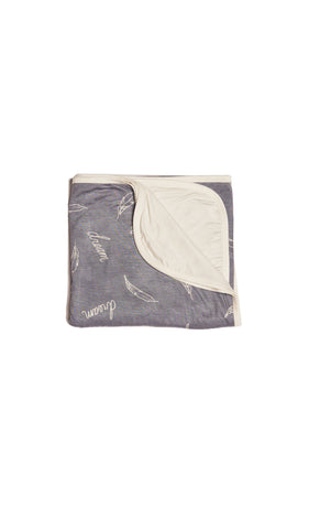 Dream Swaddle Blanket folded into a square with print showing on one side and reversible contrast solid showing on other side of fold down flap.