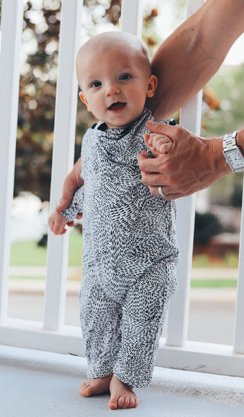 Twilight Romper 2-Piece. Baby boy standing with arms held by dad wearing long sleeve romper with matching reversible bib worn showing print side.