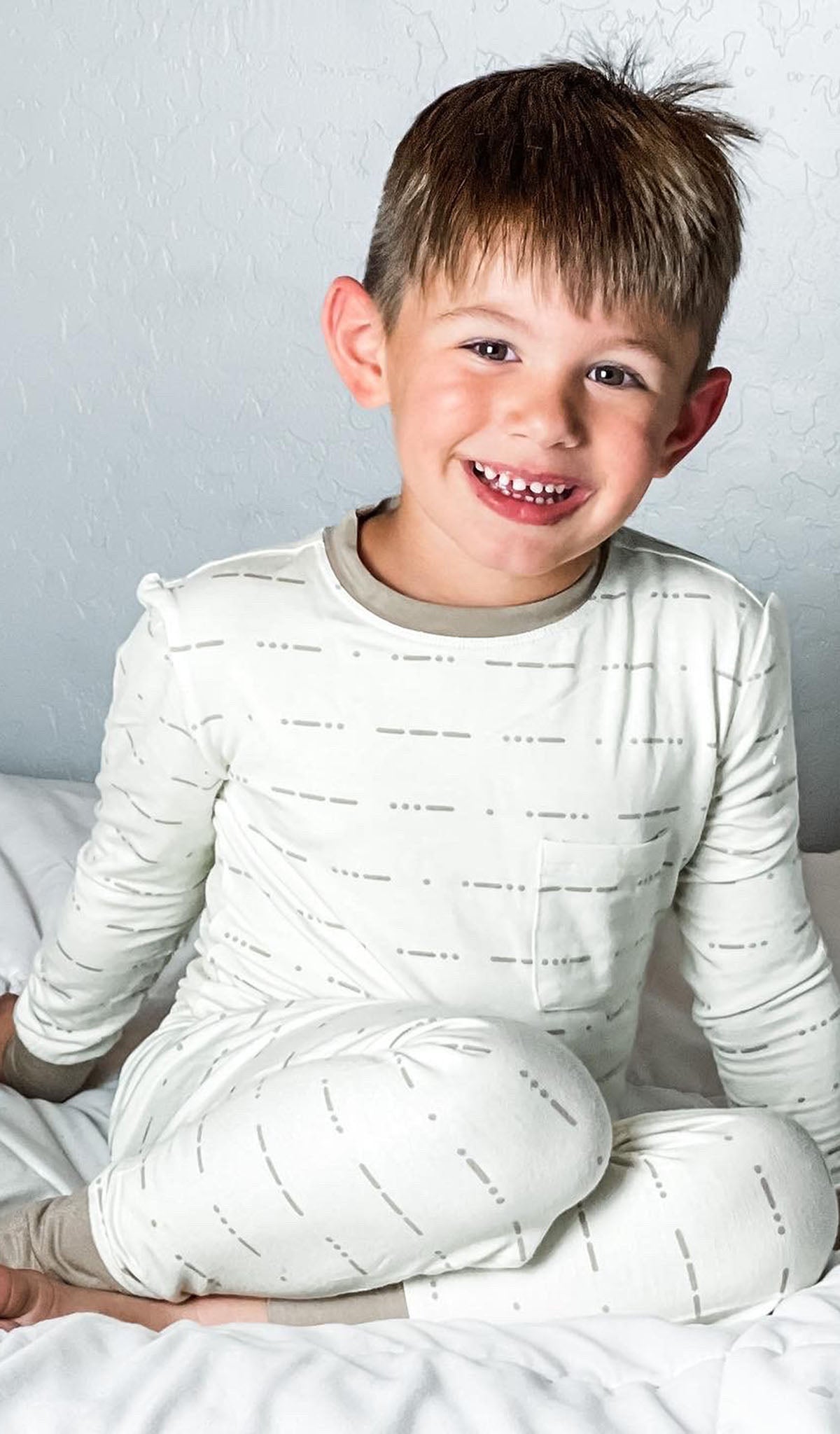 Love Emerson Kids 2-Piece Pant PJ worn by little boy sitting on his bed.
