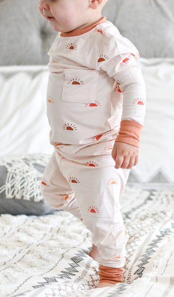 Sunrise Emerson Baby 2-Piece Pant PJ worn by baby standing on blanket.