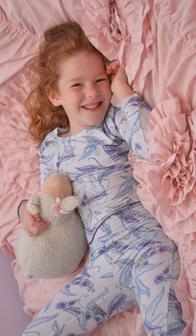 Sparrow Charlie Kids 3-Piece Pant PJ. Little girl wearing Charlie long sleeve top and pant from 3-Piece PJ set while laying in bed with lamb plush.