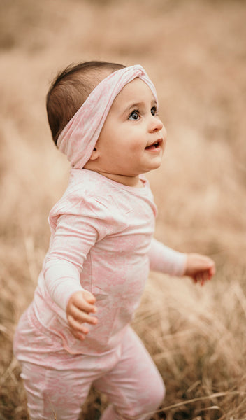 Pink Chantilly Charlie Kids 3-Piece Pant PJ. Outdoor lifestyle shot of side view of toddler girl wearing long sleeve top, pant and matching headwrap from  Charlie 3-Piece PJ set.
