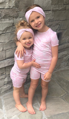 Pink Chantilly Bella Kids 3-Piece Short PJ. 2 girls hugging, both wearing short sleeve top and short with matching headwraps.