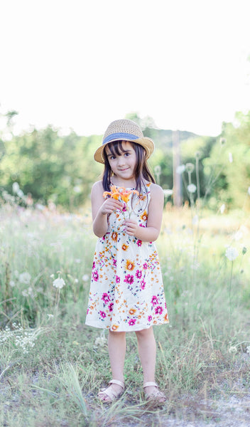 Vintage Floral Catalina Kids Dress worn by little girl smiling in a grass field while holding a flower.