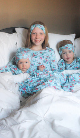Azure Mist Teal Charlie Kids 3-Piece Pant PJ. Girl and toddler girl wearing Charlie long sleeve top, pant and matching headwrap from 3-Piece PJ set sitting in bed with their baby sister in matching Ruffle Kimono 3-Piece Set.