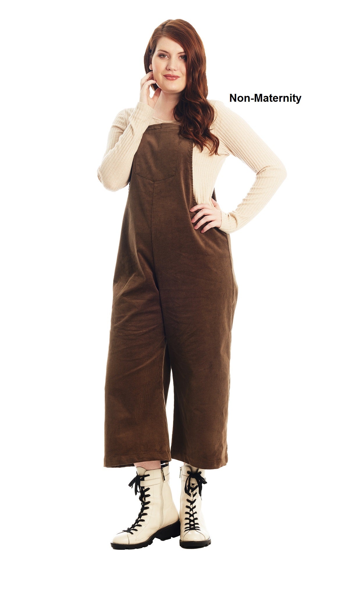 Olive Carlita overall worn by woman as non-pregnant style with one hand on her hip and other hand touching her face..