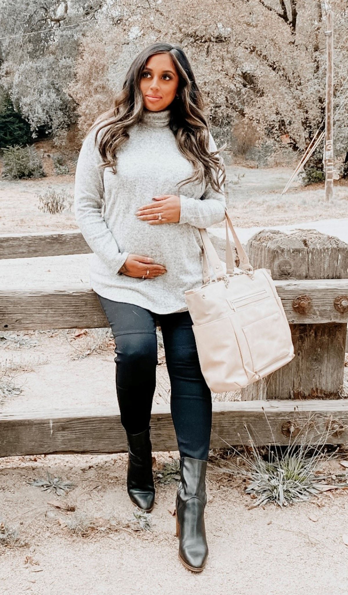 Heather Grey Teresa sweater worn by pregnant woman leaning on fence.