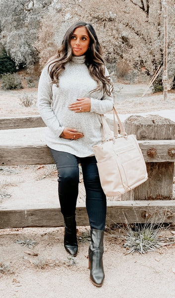 Heather Grey Teresa sweater worn by pregnant woman leaning on fence.