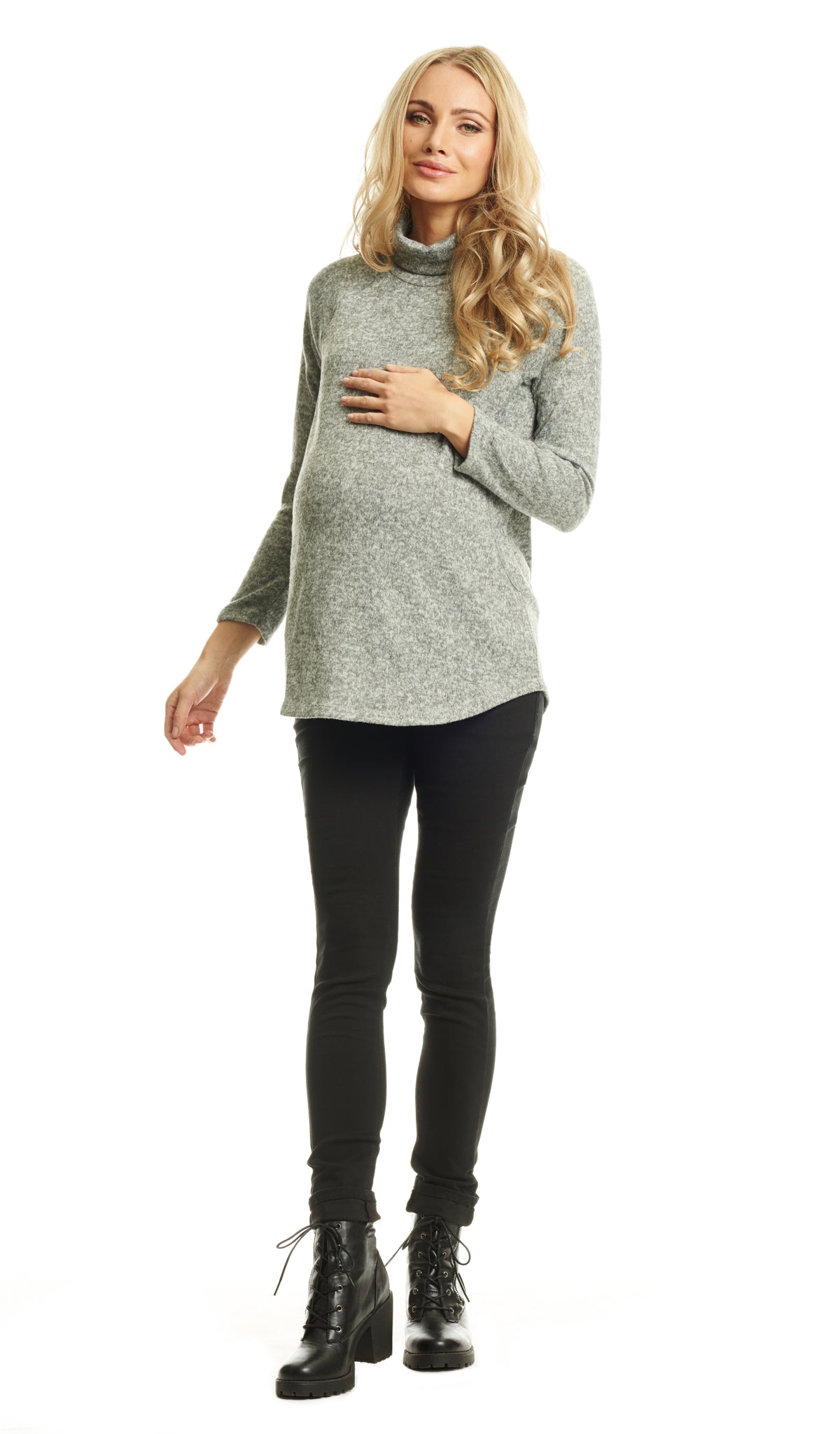 Heather Grey Teresa Sweater. Full length shot of pregnant woman wearing Teresa Sweater with one hand on her belly with black pant and black booties.