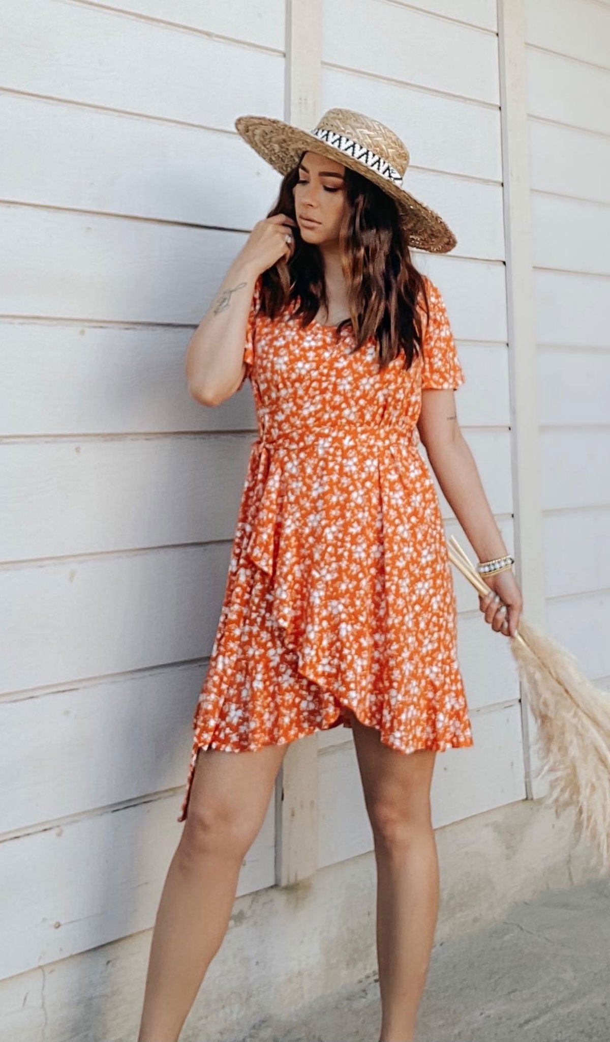 Citrus Floral Kristi Dress worn by woman wearing hat with one hand touching her hair.