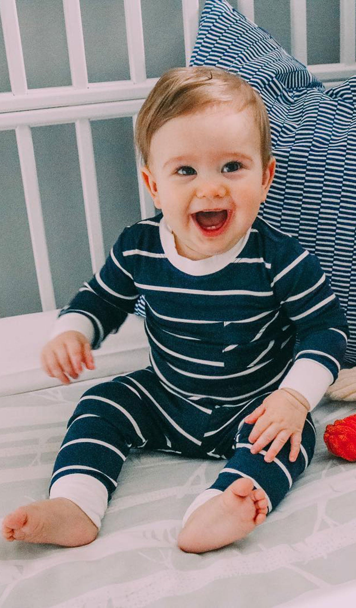 Navy Emerson Baby 2-Piece Pant PJ. Lifestyle shot of smiling boy sitting and wearing Emerson.