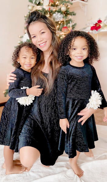 Black Aurora dress worn by woman who is kneeling and hugging two little girls wearing matching Kendyl Dresses.