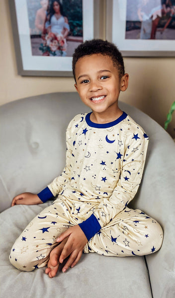 Twinkle Emerson Kids 2-Piece Pant PJ. Lifestyle shot of smiling boy sitting in a chair wearing Emerson.
