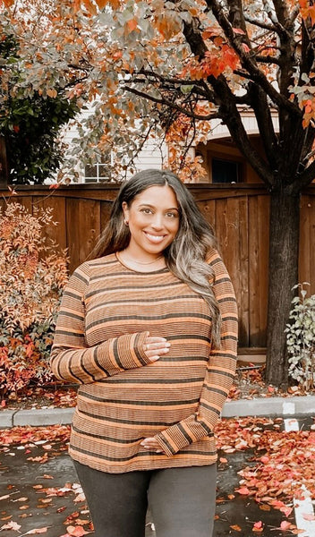 Mustard Stripe Ashley sweater worn by pregnant woman cradling her belly while standing outside.